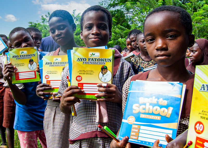 Children happily holding books recieved at Ayo Fatokun Foundation